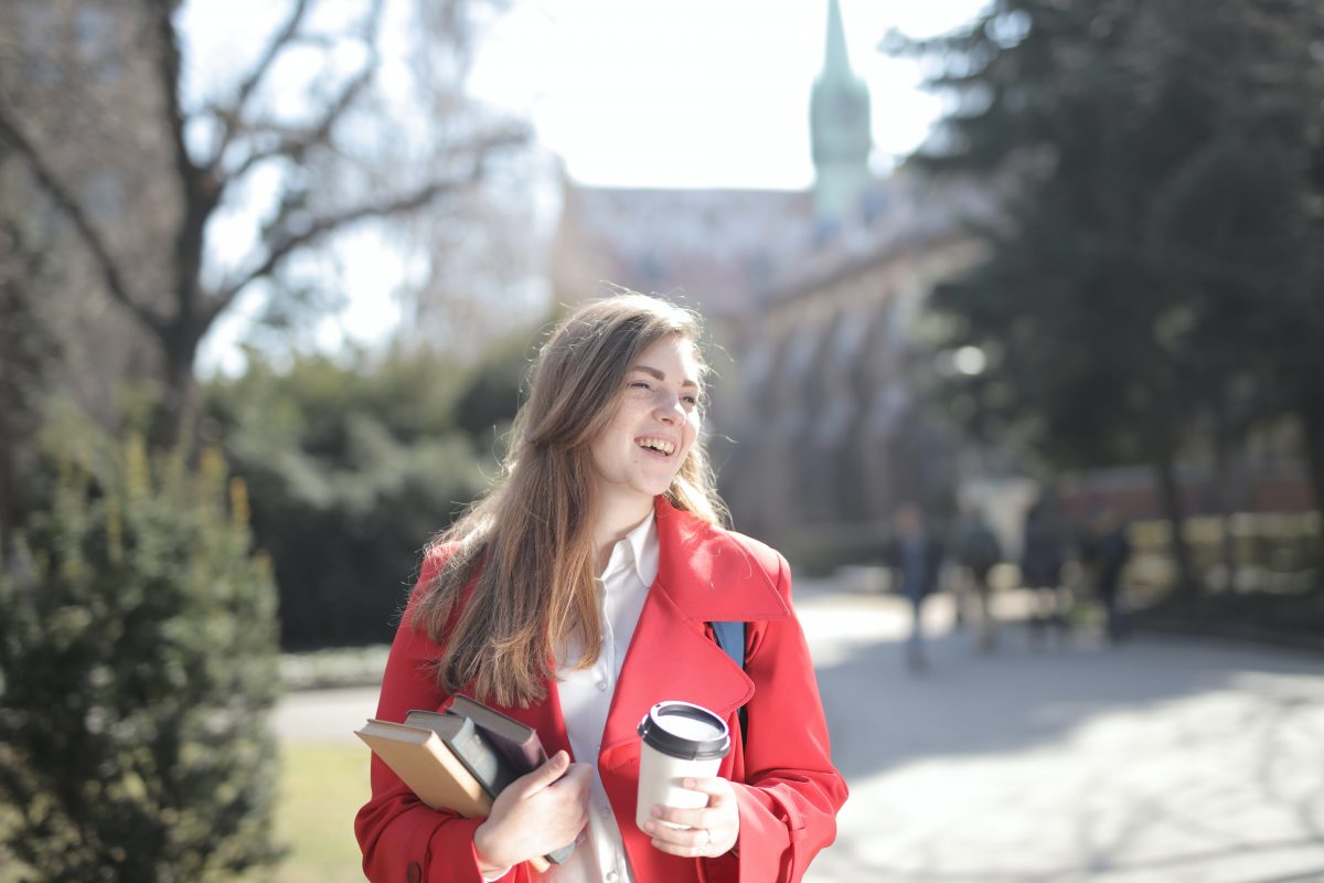 university student holding coffee glad she received a prepaid card